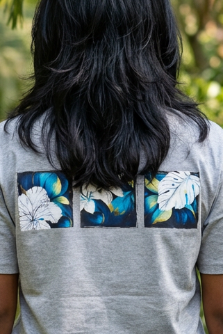 Person wearing a gray t-shirt with floral designs in a tropical setting